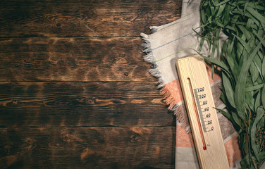 Eucalyptus bath broom, thermometer and a towel on a bathhouse table flat lay background with copy...
