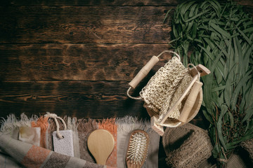 Eucalyptus bath broom and other bathhouse accessories on a wooden table flat lay background with copy space.