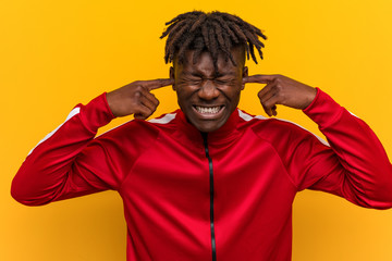 Young fitness black man covering ears with his hands.