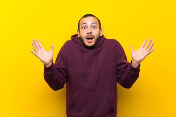 Naklejka premium Colombian man with sweatshirt over yellow wall with shocked facial expression