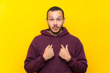 Colombian man with sweatshirt over yellow wall with surprise facial expression