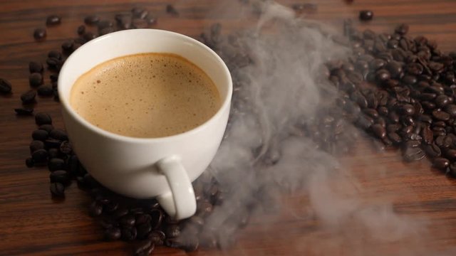 Slowmotion Pan shot of coffee cup surrounded by coffee beans.