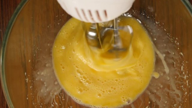 Slow motion crop shot of woman preparing homemade omelette mixing with whisk eggs.