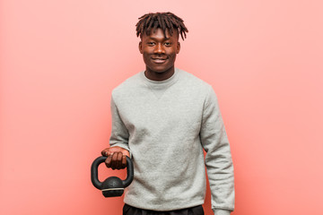 Young fitness black man holding a dumbbell happy, smiling and cheerful.