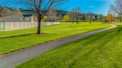 Panorama Paved pathway and trees on a lush grassy terrain in the middle of houses