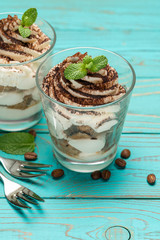Classic tiramisu dessert in a glass on blue wooden background