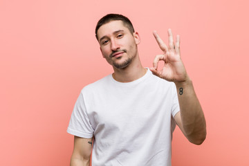 Young casual man cheerful and confident showing ok gesture.