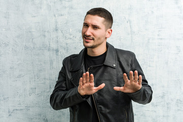 Young rocker man rejecting someone showing a gesture of disgust.