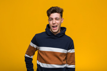 Fototapeta premium Young cool man wearing a hoodie winking, funny, friendly and carefree.
