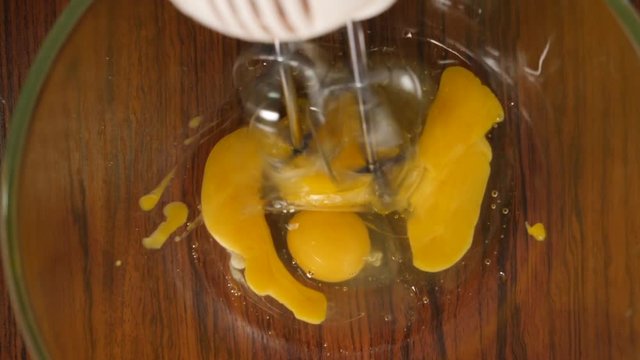 Slow motion crop shot of woman preparing homemade omelette mixing with whisk eggs.