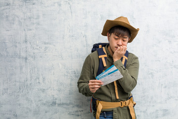 Young explorer chinese man holding an air tickets biting nails, nervous and very anxious