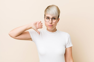 Young authentic natural woman wearing a white shirt showing a dislike gesture, thumbs down....