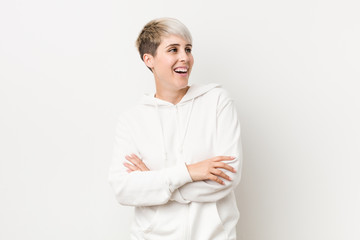 Young curvy woman wearing a white hoodie smiling confident with crossed arms.