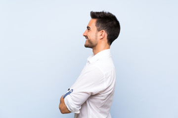 Handsome young man over isolated blue background in lateral position