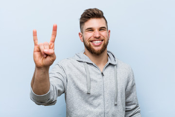 Fototapeta premium Young handsome fitness man showing a horns gesture as a revolution concept.