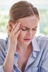 Stressed Businesswoman Suffering With Headache In Office