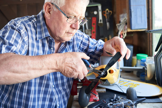 Senior Man Working On Model Radio Controlled Aeroplane In Shed At Home