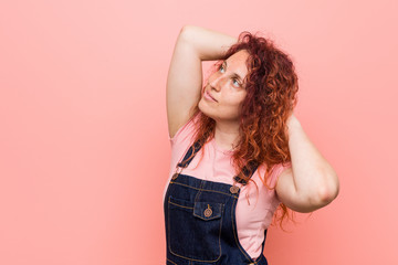 Young pretty ginger redhead woman wearing a jeans dungaree stretching arms, relaxed position.