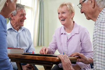 Group Of Retired Friends Playing Board Game At Social Club