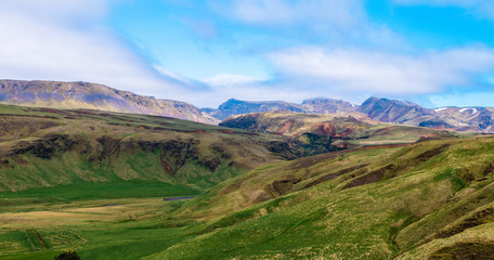 Fototapeta premium Icelandic landscape green field with mountains in the background