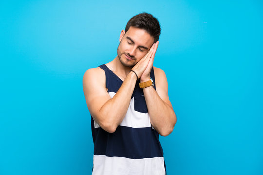 Handsome young man over isolated background making sleep gesture in dorable expression