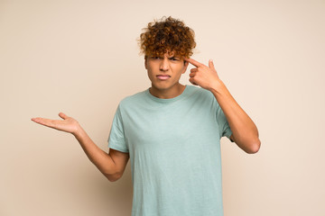 African american man with green shirt making the gesture of madness putting finger on the head