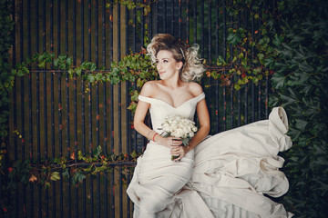 Beautiful bride in a long white dress. Woman with bouquet of flowers. Lady lies on the ground