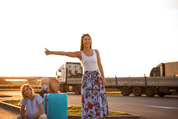 Two beautiful young friends are hitchhiking on the road, one is optimistic and the other is a...