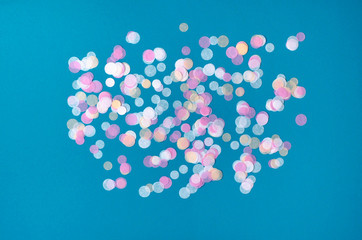 Turquoise background with many round multicolored confetti.