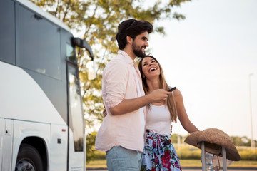 The young couple are happy because they have just made online reservation of a beautiful hotel at a very reasonable price, while waiting to board the bus.