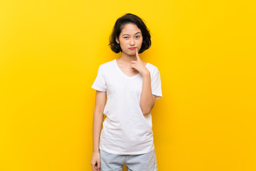 Asian young woman over isolated yellow wall Looking front