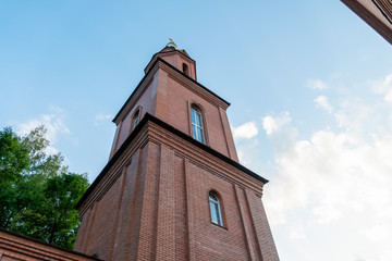 Fototapeta premium Part of a brick Orthodox church with a dome and a cross close-up against a blue sky. Orthodox cross. Photo bottom up