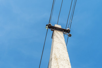 A pole with wires going out horizontally against a bright blue sky. Image has copy space. photo view from below
