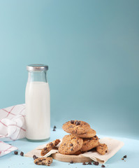 Cookies with chocolate chips and fresh milk bottles on the ground, light blue pastel colors