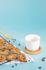 Cookies chocolate chips and coffee cup on the ground, light blue pastel colors