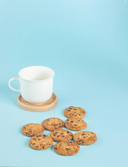 Cookies chocolate chips and coffee cup on the ground, light blue pastel colors