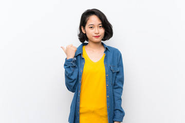 Asian young woman over isolated white background pointing to the side to present a product