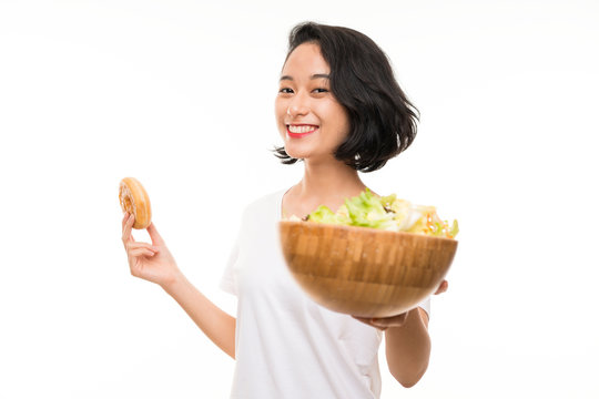 Asian young woman over isolated background with salad and donut