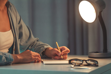 Female with eco pen writing  something on paper and working using notebook. Woman write thoughts in...