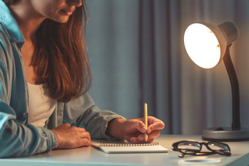 Female with eco pen writing  something on paper and working using notebook. Woman write thoughts in...