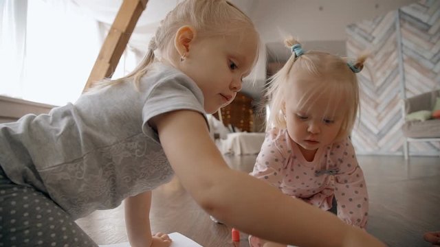 Kids sitting on the floor inside flat and playing or dray