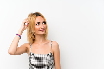 Fototapeta premium Young blonde woman over isolated white having doubts while scratching head