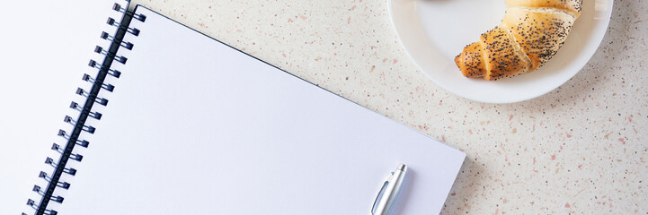 table with empty notebook and plate with twirl panorama