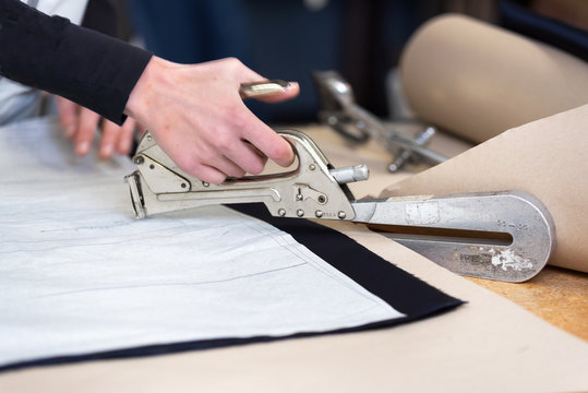 Dressmaker designer stapling fabric pattern at garment industry . 