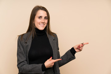 Young woman over isolated wall pointing finger to the side