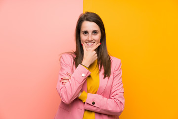 Young woman with pink suit over colorful background laughing