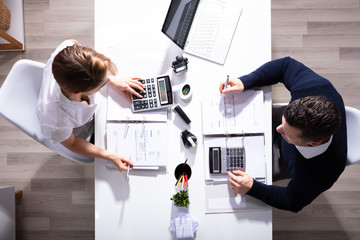 Male And Female Businesspeople Calculating Invoice