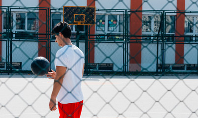 Two strong basketball player playing ball on an urban city basketball court, while wearing black and red outfit.