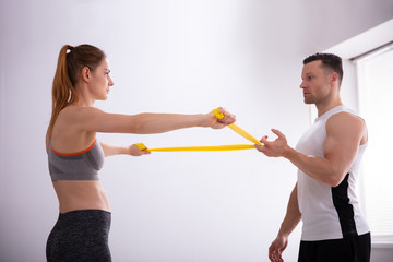 Young Woman With Gym Trainer Doing Exercise