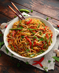 Chow mein, noodles and vegetables dish with wooden chopsticks